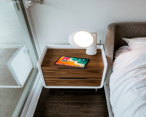 A smartphone on a bedside table with warm lamp light